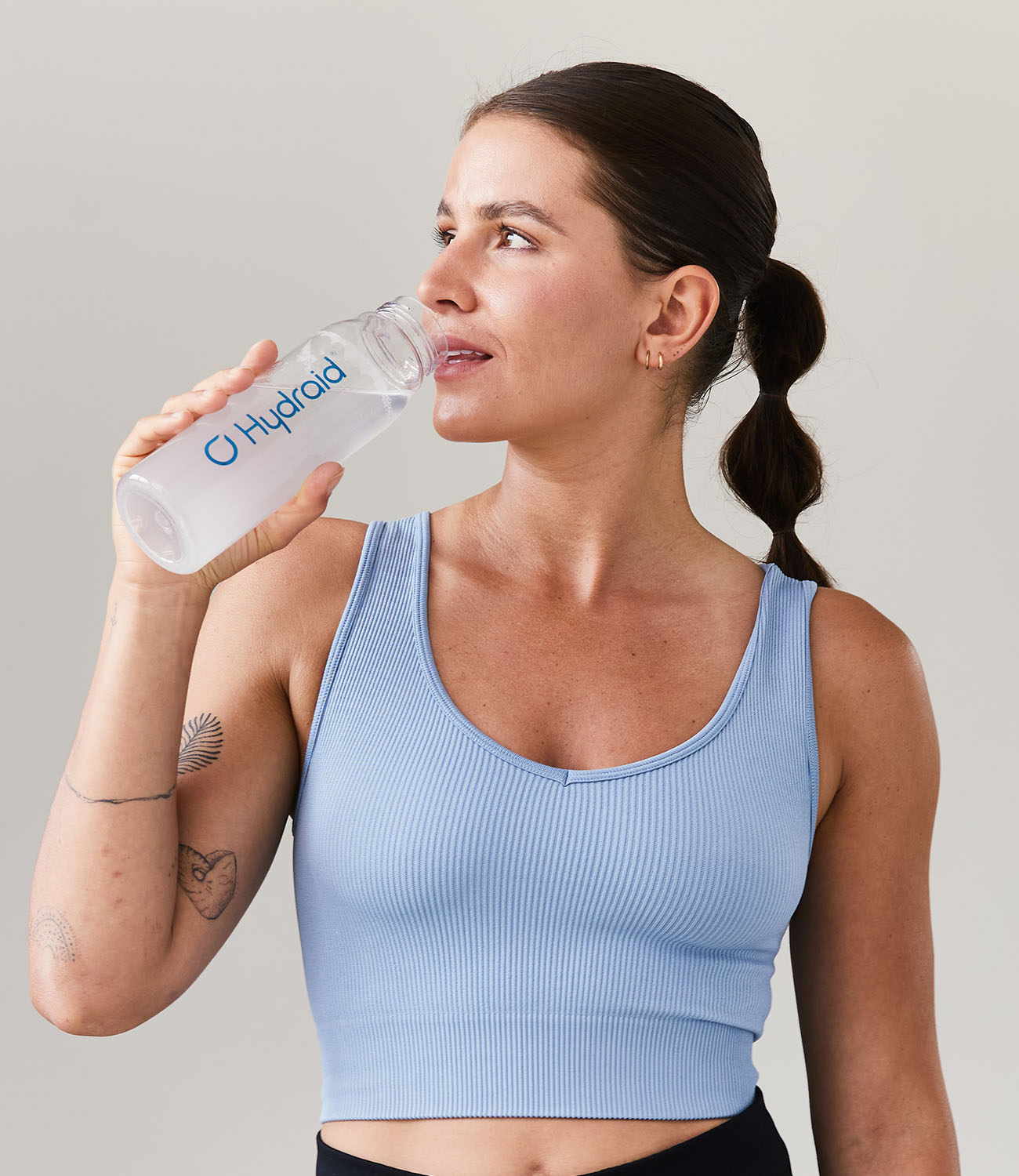 Women trinking Hydration Helper® Lemon out of Hydraid® Bottle