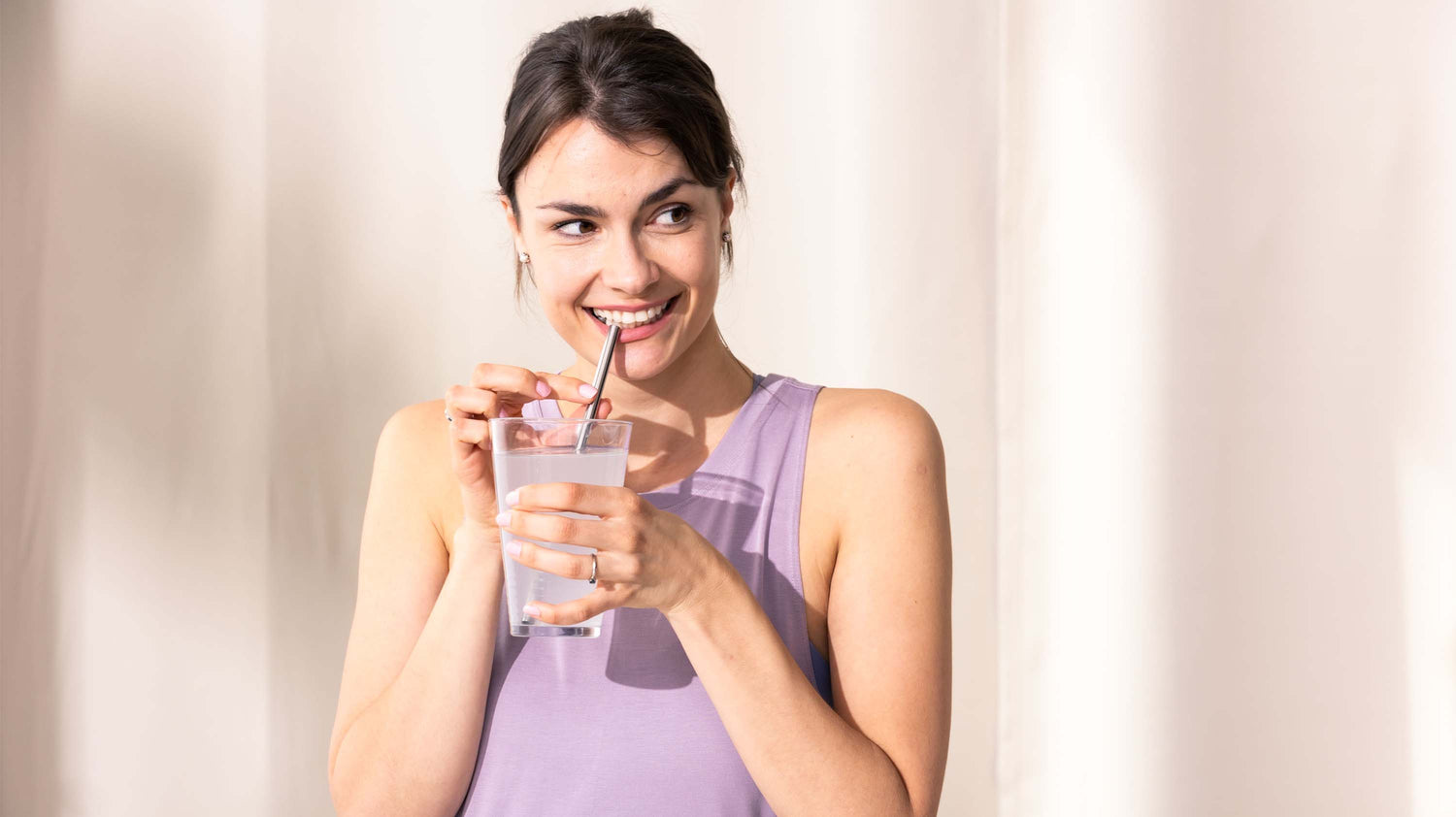 Junge Frau trinkt ein Glas Wasser mit Hydration Helper
